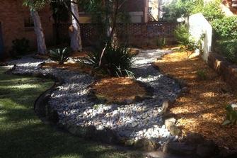 Landscaping Concept - Why settle for the ordinary when, as this picture shows it is possible to bring a breath of new life to an otherwise out of the way area with the use of Pinebark Mulch and White Pebbles. Creating a garden that will stop people in their tracks.